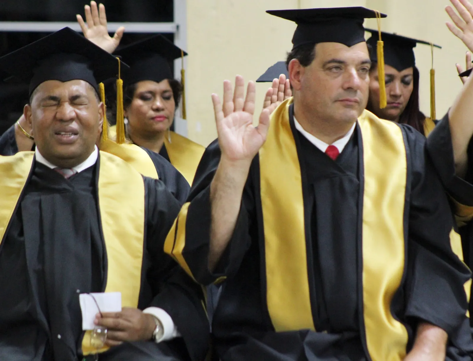 Graduandos de UCASA con toga levantando la mano durante el juramento